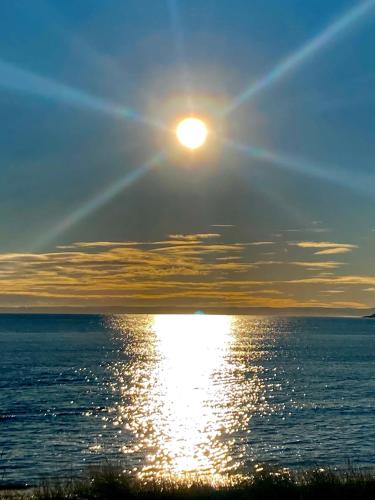 a sun setting over the ocean with the sun reflecting on the water at The Old Manor House,Carnoustie in Panbride