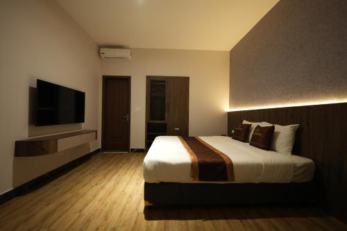 a hotel room with a bed and a flat screen tv at Cat Ba Viet Hoa Hotel & Residence - Pool & Bar in Cat Ba