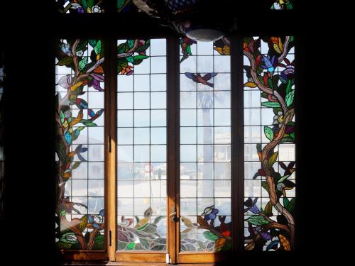 a window with a stained glass window with birds on it at Villa Tina Hotel in Viareggio