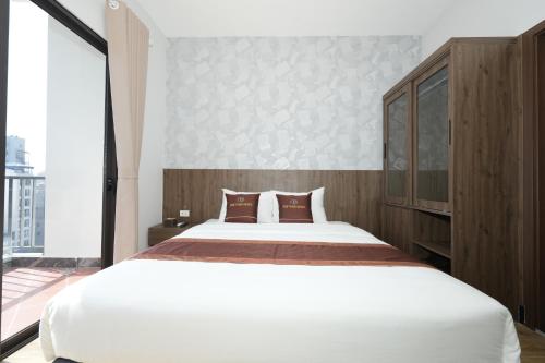 a bedroom with a large white bed and a large window at Cat Ba Viet Hoa Hotel & Residence - Pool & Bar in Cat Ba