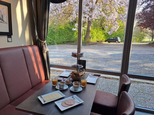 a table with two cups of coffee next to a window at B&B Uit de Kunst Anna Paulowna in Bingelrade