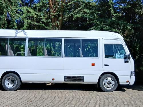 a white bus is parked on a street at Matteos Italian Restaurant,Bar & Accommodation in Naivasha
