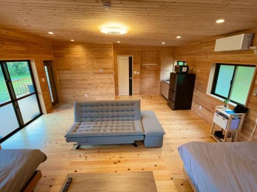 a living room with a blue couch in a room with wooden walls at 満天の星空に出会える宿 やんばるtgコテージ in Ujimi