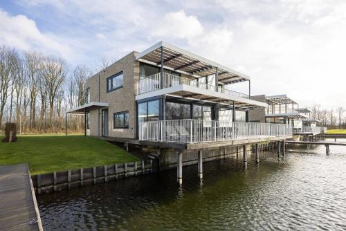 a house on a dock on a body of water at Hello Zeeland - Water villa Veerse Wende with fully fenced terrace in Arnemuiden