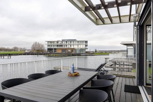 a deck with a table and chairs and a building at Hello Zeeland - Water villa Veerse Wende with fully fenced terrace in Arnemuiden