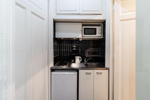 une petite cuisine avec un évier et un micro-ondes dans l'établissement Champs Elysées Apartment, à Paris