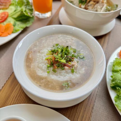 a bowl of soup on a table with plates of food at Asoca Hotel Luang Prabang in Luang Prabang