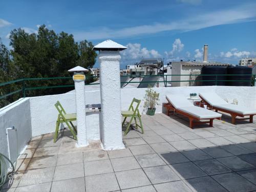 a patio with chairs and tables on a roof at Nikos Sunset Penthouse in Mastambás