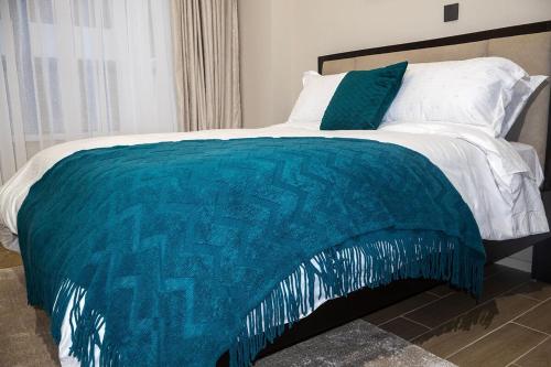 a bed with a turquoise and white comforter at Cozy & Luxury Apartment Lavington, Nairobi in Nairobi