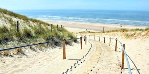 a stairway leading to a sandy beach next to the ocean at Slotje in Egmond aan den Hoef