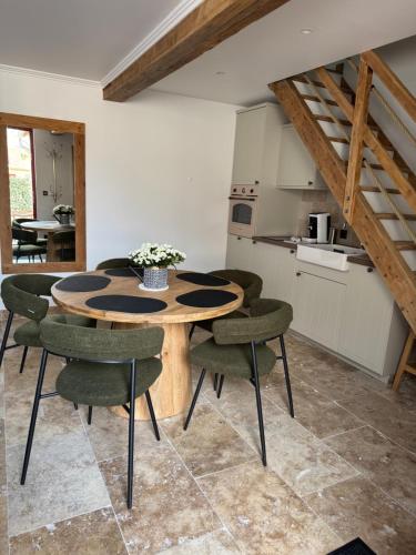 une salle à manger avec une table en bois et des chaises vertes dans l'établissement Le cottage Maisonnette dans corps de ferme, à Allainville