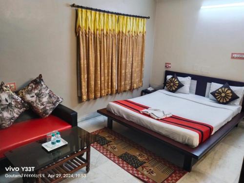a bedroom with a bed and a red couch at AKG INN Kolkata in Salt Lake City