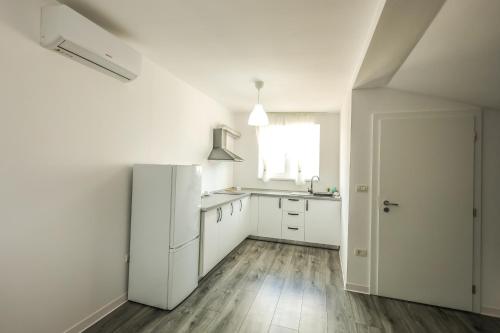 a white kitchen with a refrigerator and a window at Casa Chirila in Giarmata Vii