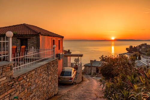 a house with a car parked on a street with a sunset at Vista Mare in Afissos