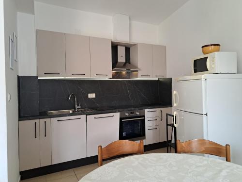 a kitchen with white cabinets and a white refrigerator at Apartments Ružica in Zaostrog