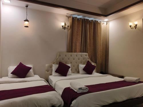 two beds in a hotel room with white and purple pillows at Hotel Agra Grande By Goyal Hoteliers in Agra
