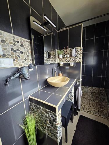 La salle de bains est pourvue d'un lavabo en bois et de carrelage noir. dans l'établissement Chez Stéphane et Patricia, à Vertaizon