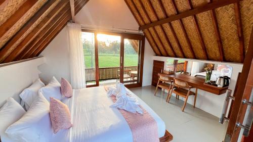 a bedroom with a white bed with a desk and a table at Lila Sari Guest House Rom Only in Penginyahan