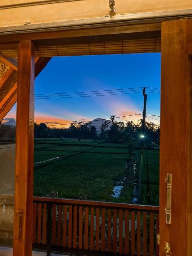 a view out of a porch window at sunset at Lila Sari Guest House Rom Only in Penginyahan