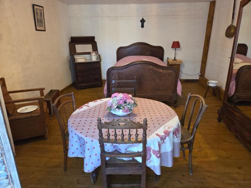 Cette chambre comprend une table avec des fleurs. dans l'établissement Chambre insolite années 40 à Omaha Beach pour la nuit du Jour J la plus longue, à Saint-Laurent-sur-Mer