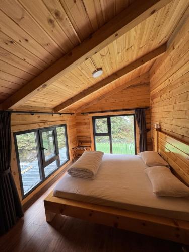 a bed in a room with wooden walls and windows at Ayder Villa Gencal King in Ayder Yaylasi