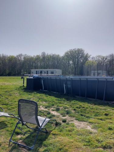 a chair sitting in a field with trash cans at Comme chez Moi - Mobile-home dans camping à la ferme in Arcomps