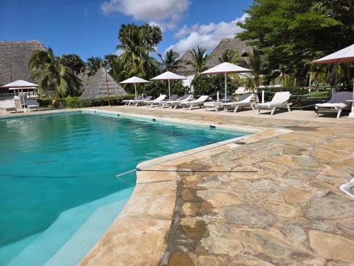 a swimming pool with chairs and umbrellas at Karibuni, Villa 107, Beachfront Stay with Restaurant, Pool & Bar in Malindi