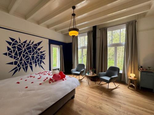 a bedroom with a large bed with two chairs at POSTEN nordic cuisine in Frederiksoord