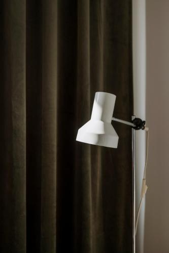 a white lamp sitting in front of a curtain at Apartment for friends & families in Tallinn