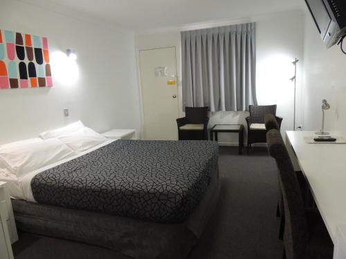 グラッドストンにあるPark View Motelのベッド、テーブル、椅子が備わるホテルルームです。