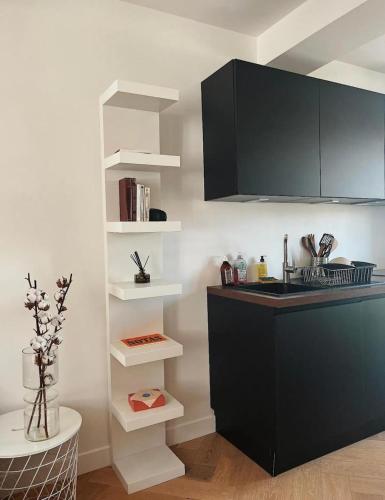 une cuisine avec un comptoir noir et des étagères blanches dans l'établissement Nice vieille ville appartement design, proche de tout, à Nice