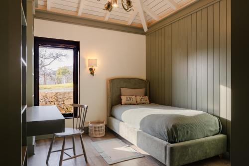 a bedroom with a bed and a desk and a window at Vinte-Quinta da Boavista in Ponte de Lima
