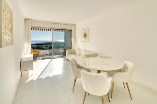 un salon blanc avec une table et des chaises dans l'établissement Spacieux 3 pièces rénové avec terrasse et vue mer entre Monaco et Menton, à Roquebrune-Cap-Martin