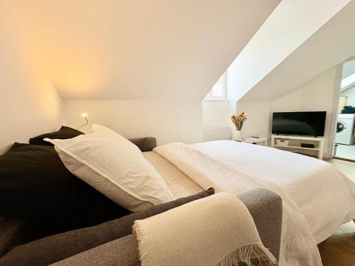 Cette chambre comprend un lit avec des draps blancs et une télévision. dans l'établissement Le cœur des Alpes, à Grenoble