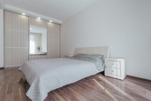 a white bedroom with a bed and a mirror at Modern Flat near City Center with Parking, Smart TV & Wi-Fi in Rīga
