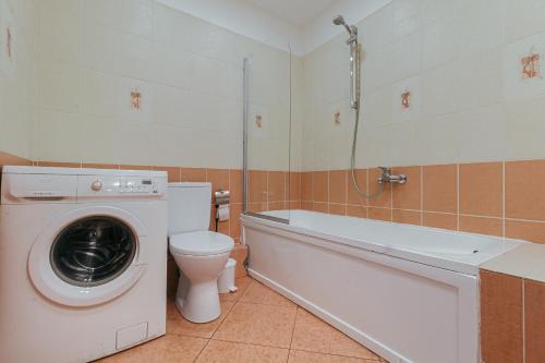 a bathroom with a washing machine and a toilet at Modern Flat near City Center with Parking, Smart TV & Wi-Fi in Rīga