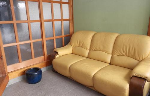 a yellow couch in a room with a window at GLOCE sado ベースキャンプ 松ヶ崎 ワンちゃんと泊まれます in Sado