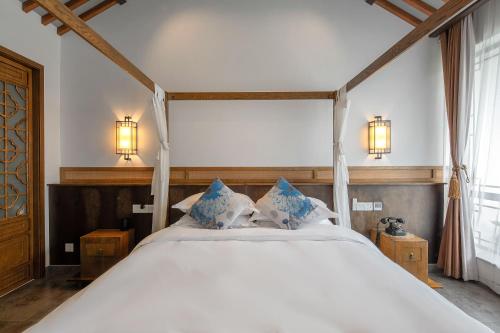 a bedroom with a large white bed with blue pillows at 南京又见江南民宿 in Nanjing