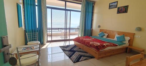 a bedroom with a bed and a balcony with a view at RUDRA Retreat in Hawālbāgh
