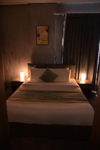 a bedroom with a large bed with two lights on it at Dahlia Venti Hotel Apartment- formerly days inn by dahlia - Al Jahra in Jahra