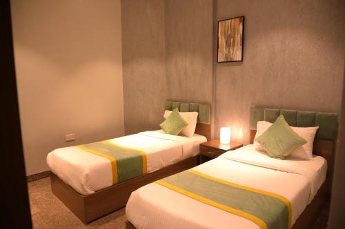 a hotel room with two beds and a lamp at Dahlia Venti Hotel Apartment- formerly days inn by dahlia - Al Jahra in Jahra