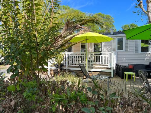 une maison avec une terrasse dotée d'une table et d'un parasol dans l'établissement Mobil-home de charme avec deux terrasses, à Vias
