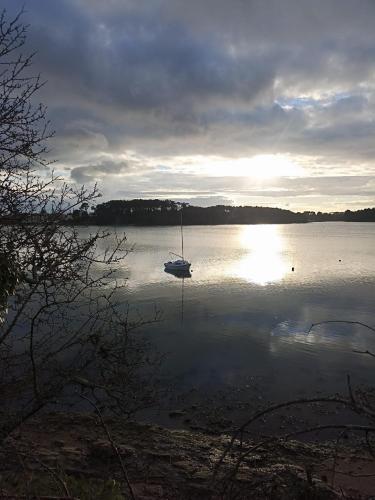 a boat sitting on a lake with the sun setting at La Parenthèse du golfe chambre d hôte in Arradon