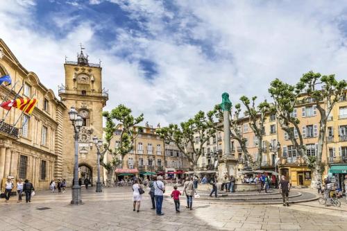 a group of people walking in a plaza with a clock tower at T2 charmant avec mezzanine au cœur d'Aix in Aix-en-Provence