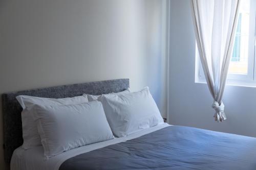 a bedroom with a bed with white pillows and a window at Numero 5 in Bari
