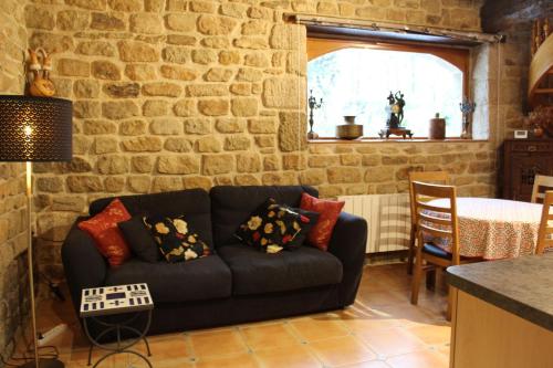 - un salon avec un canapé au mur en pierre dans l'établissement Le Clos de Penguily Brocéliande 16 couchages SPA, à Mauron