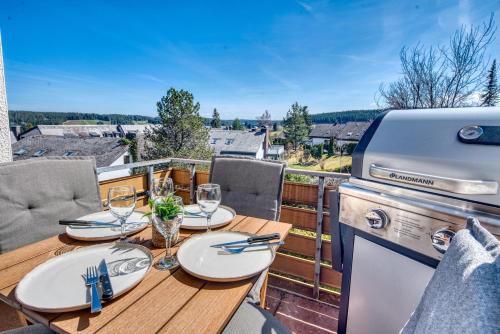 einen Tisch mit Weingläsern und einen Grill auf dem Balkon in der Unterkunft Aussicht auf Natur, Pool, Grill, Kino, Sauna in Schönwald