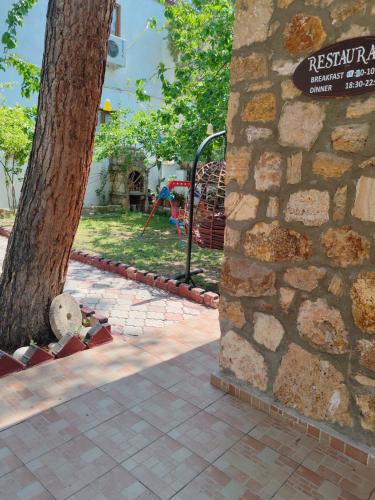 a tree next to a stone wall with a playground at Pınar Vintage House in Pamukkale