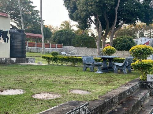 two benches and a table in a park at Mussagy Guest House in Vila Praia Do Bilene