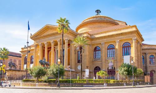 a large building with palm trees in front of it at Massimo Rooms and suite in Palermo